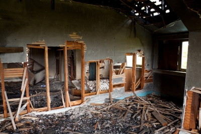 A home damaged after a large fire. Shingles and wall parts are burned and fallen down.